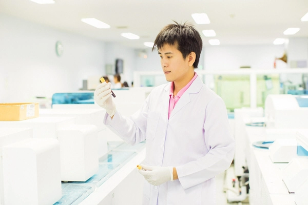 asian male doctor examines blood sample