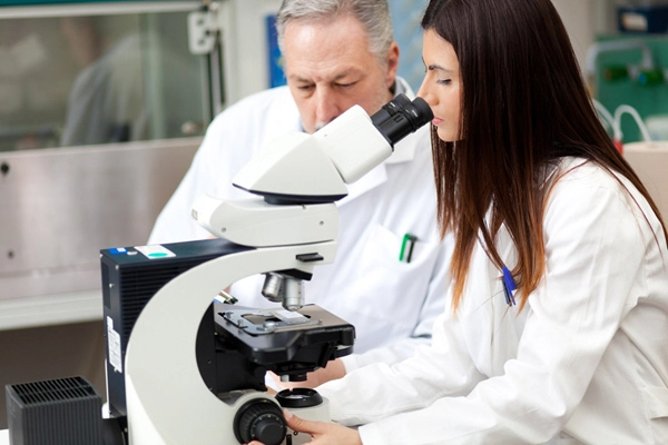 couple of scientists conducting research looking through microscope