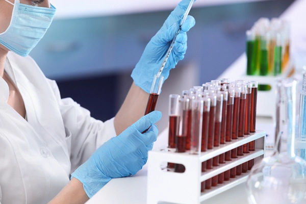 doctor doing tests on rack of tubes of blood