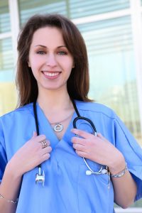 pretty young female HGH nurse outside hospital building  200x300